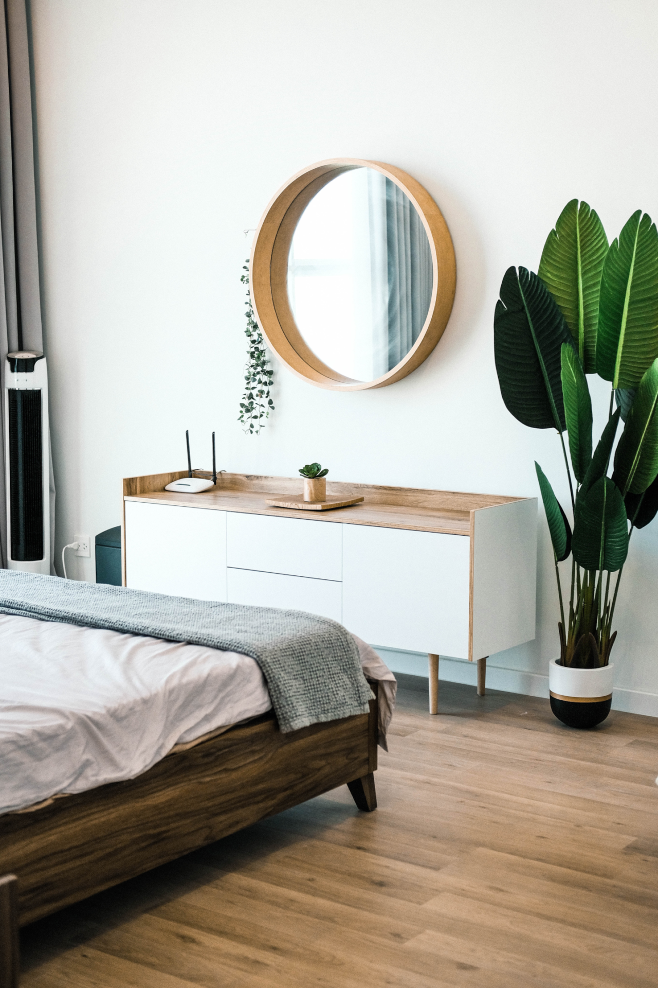 A boho style bedroom with minimalistic wood bed frame and credenza