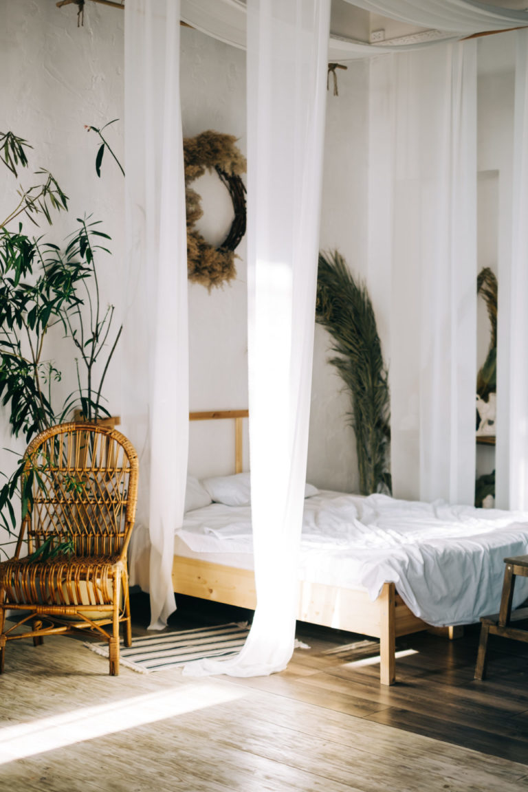 Boho bedroom with plants and wicker chair