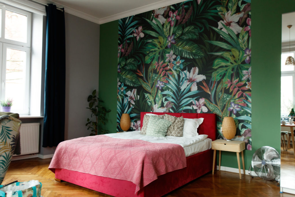 Vivid botanical wallpaper in a Boho bedroom with jewel tone green accent wall